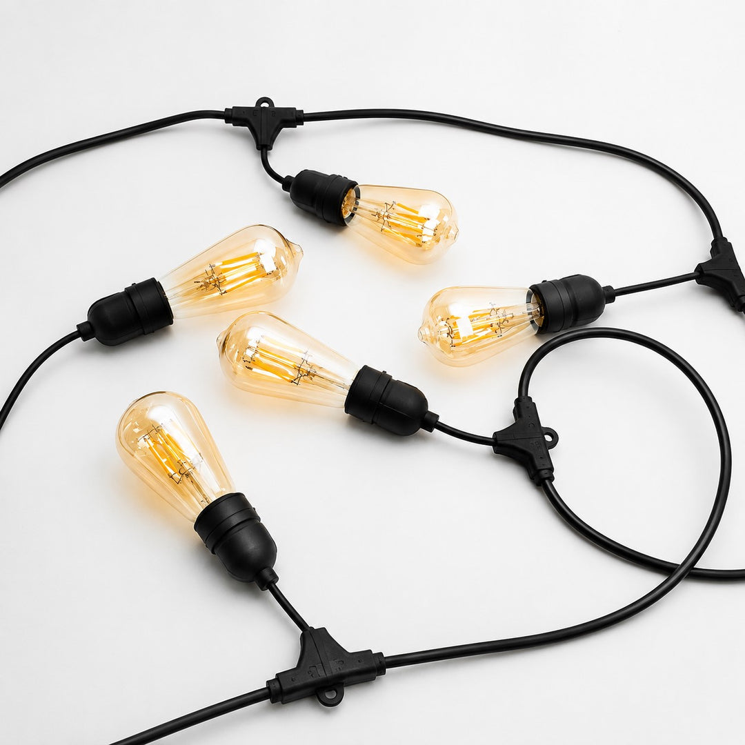 A set of six vintage-style teardrop-shaped light bulbs with clear amber glass and black sockets, connected by a black cord with toggle switches, arranged on a plain white background.